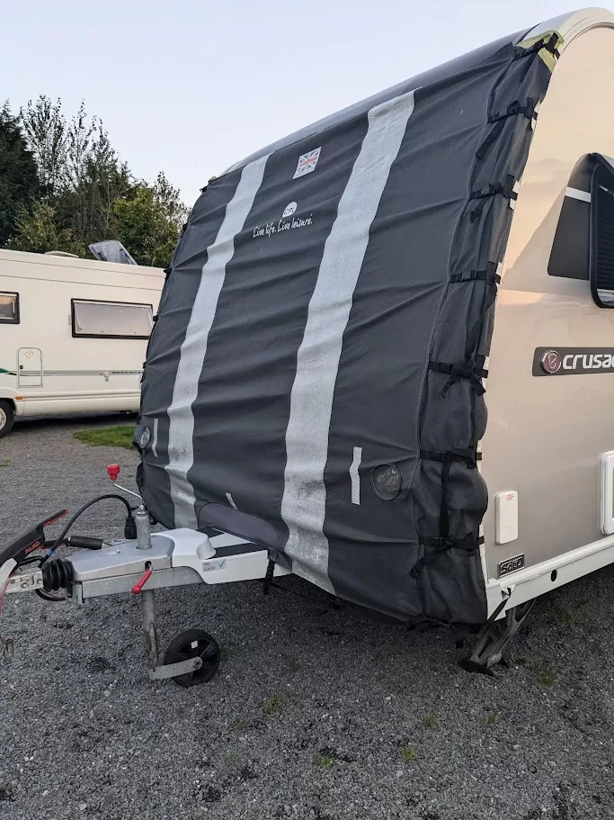 Caravan with towing cover protecting front from road debris and weather during transit